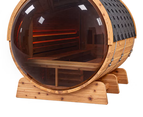 A round wooden sauna with a large curved glass front, showing wooden benches and interior lighting.