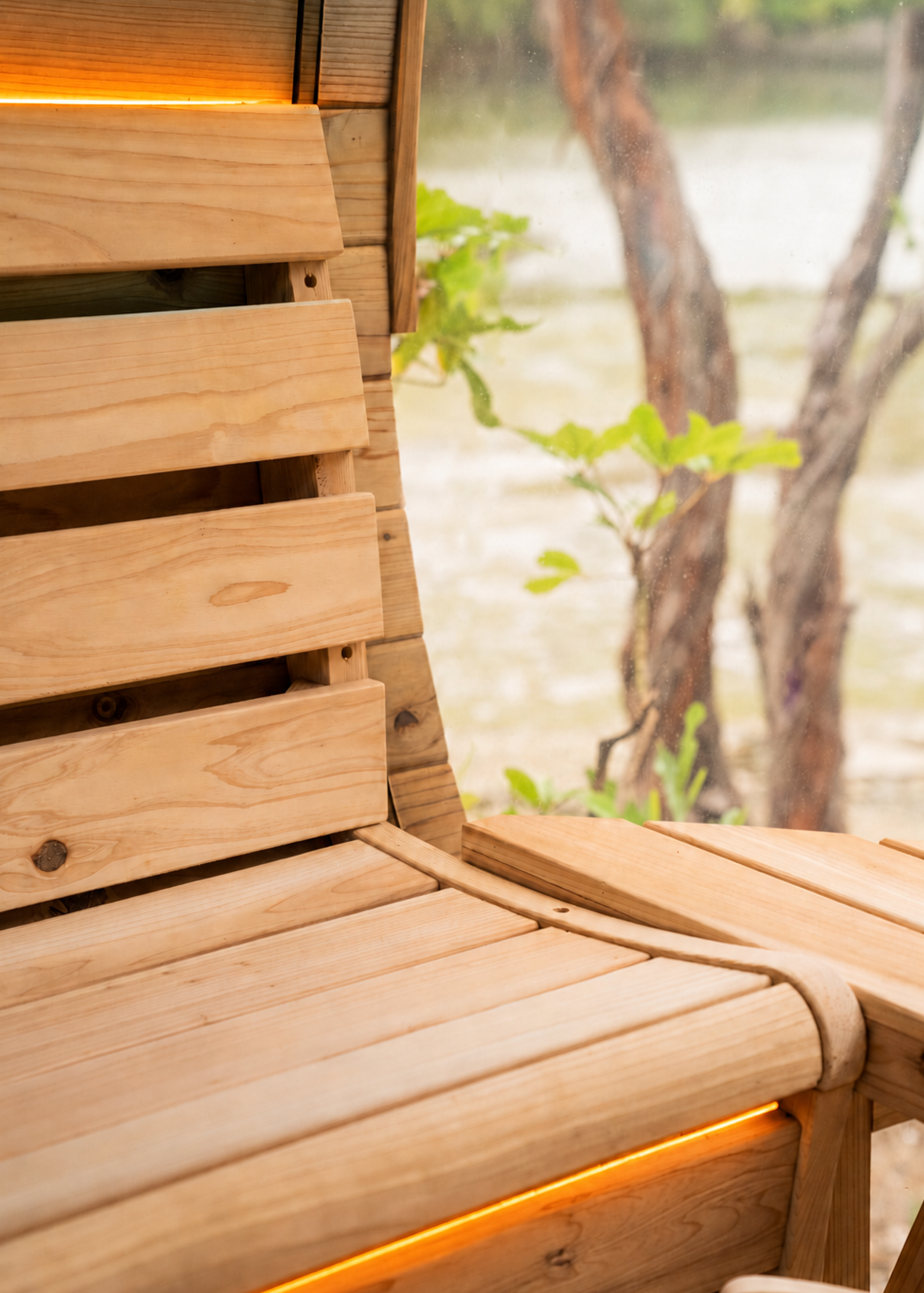 Close-up of a wooden bench with integrated orange lighting, set next to a window overlooking trees and greenery.