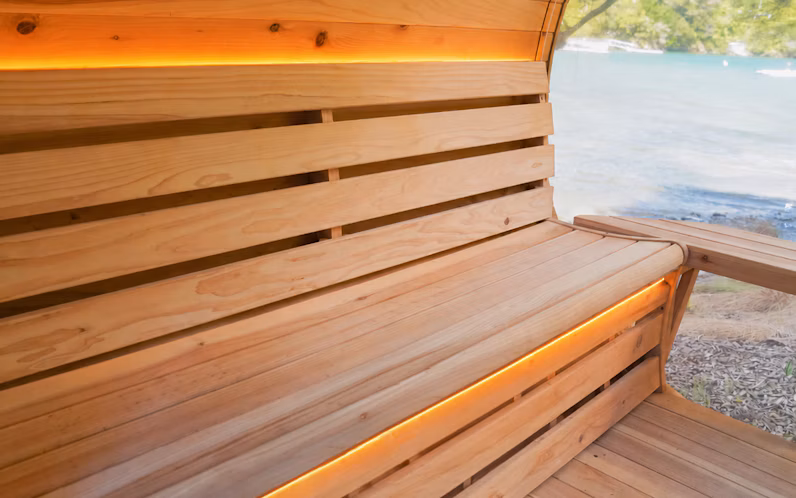 Wooden bench with warm LED lighting, set beside a large window overlooking water and trees.
