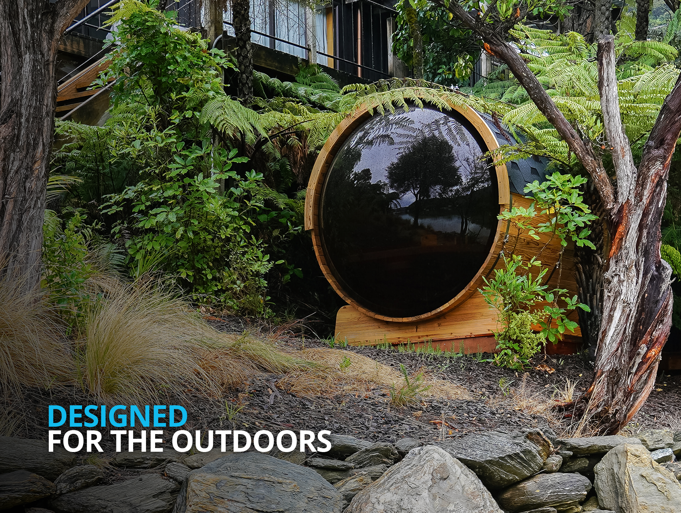 A round wooden outdoor structure with a large glass window is nestled among lush greenery and trees, with the words "Designed for the outdoors" overlaid in the foreground.