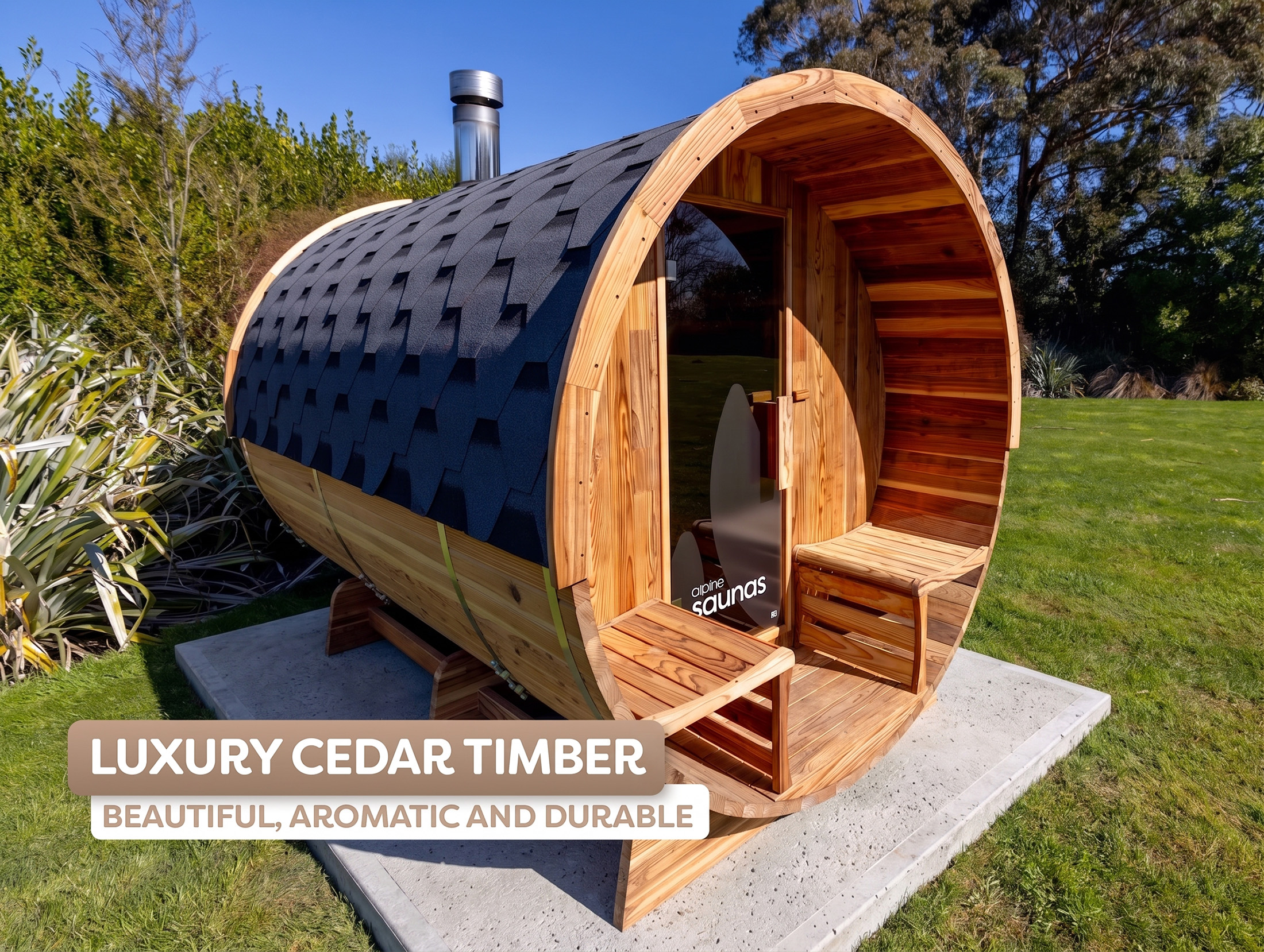 A cylindrical cedar timber outdoor sauna with a shingled roof, glass door, and two wooden benches, set on a concrete base in a grassy garden.