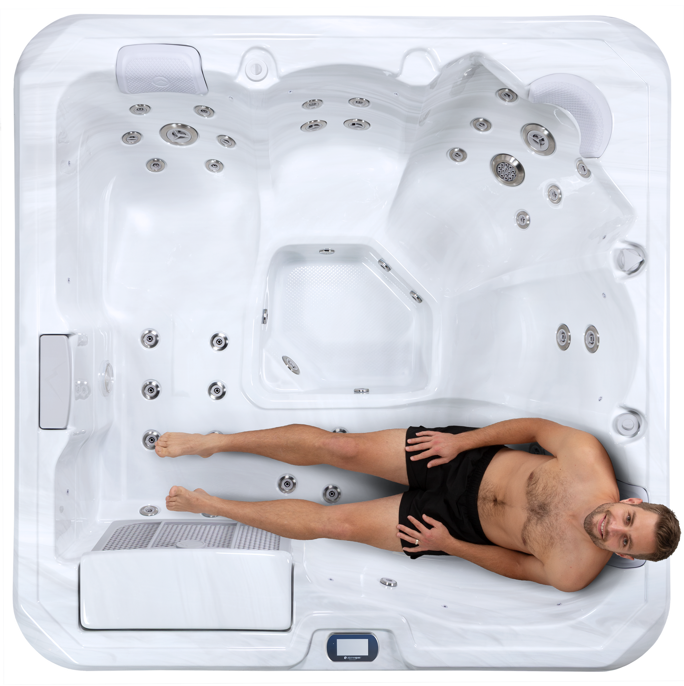 Top-down view of a man in swim trunks reclining in the lounger seat of a white, empty hot tub.
