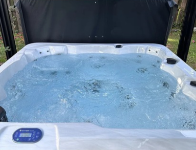 A square white spa pool filled with bubbling water is shown outdoors.
