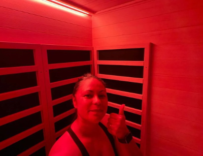 A person gives a thumbs up while standing inside a room with red lighting and wooden panelled walls.